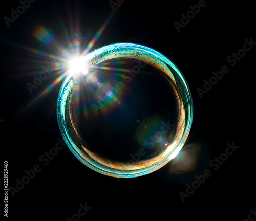 iridescent soap bubble with cinematic lens flare on black background