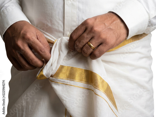 Kerala groom tying traditional white mundu with gold kasavu border
