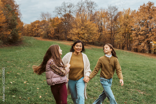 Grandmother spending time with granddaugters, walking in autumn nature.