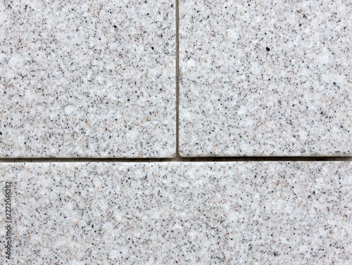 Close-up of a granite stone wall with rectangular blocks arranged in a staggered pattern, showing texture and subtle color variations.