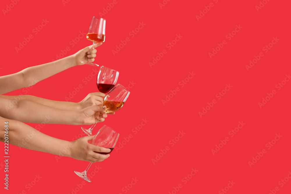 Fototapeta premium Celebration and social gathering, diverse hands holding wine glasses for a toast on a red background with copy space for party and event marketing