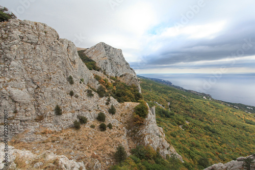 Rocky mountain slope with sea view in autumn under cloudy sky, natural landscape and scenic panorama