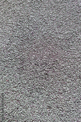 Surface densely covered with numerous small gray pebbles closely packed together, creating a rough and granular texture. Pebbles vary slightly in size and shape, providing an uneven, natural stone app