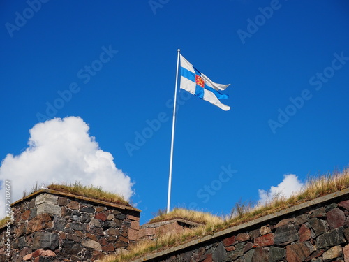 Finnish flag waving over the stone walls of Suomenlinna Fortress under blue sky