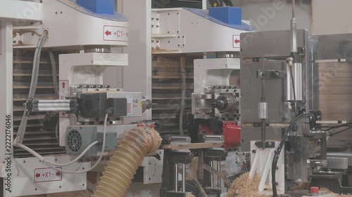 CNC woodworking machine milling a precision edge profile on a wooden board. Automated routing process creates an interlocking joint for furniture manufacturing and wood assembly.