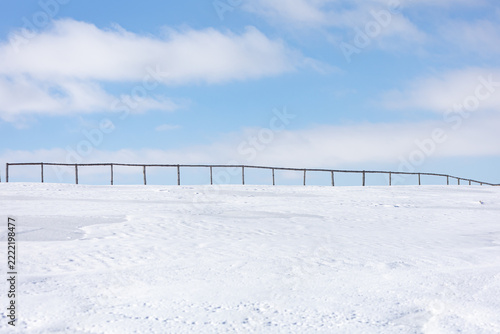 A long row of wooden posts are in the snow