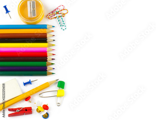 Neatly arranged colorful pencils, sharpener, eraser, paper clips, push pins, safety pins and clothespin forming a bright school and office supplies border on white