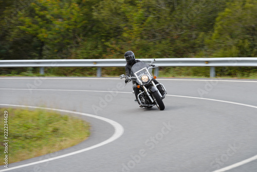 biker on a custom classic motorcycle rides down the road, road traffic