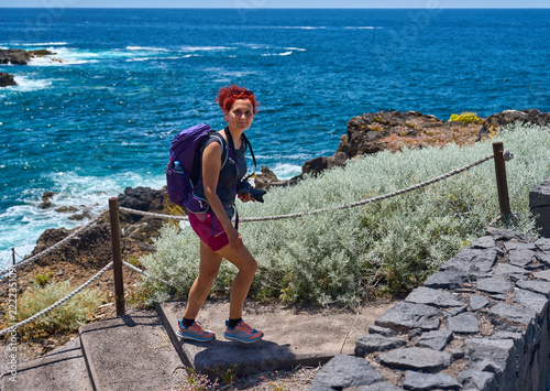 Smiling red-haired hiker with camera on the El Sauzal coastal path, Tenerife