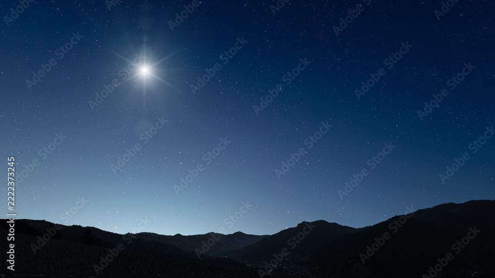 Fototapeta premium Glowing Christmas star above a peaceful mountain landscape