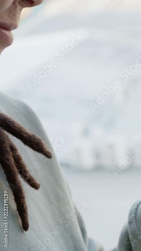 Vertical video: Window light nudging face shifting and smiling, crewneck and dreads, copy space