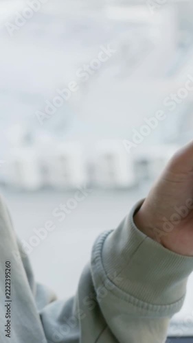 Vertical video: Tilting person gazing at window, cam moving closer, wearing crewneck and dreads