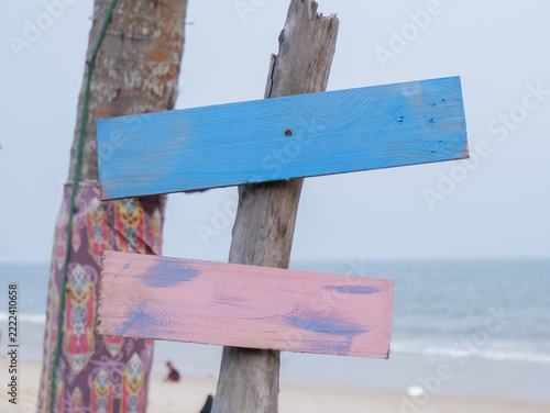 Blank wooden signboards on a beach post with blue and pink wooden planks for mockup and design