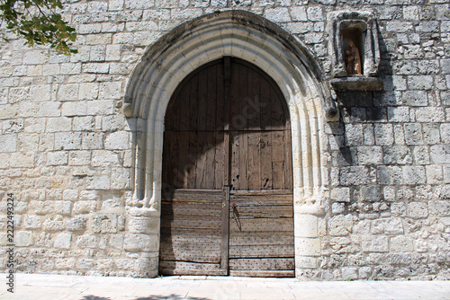 Portail en arc brisé et porte en bois brut d'une ancienne église en pierre blanche