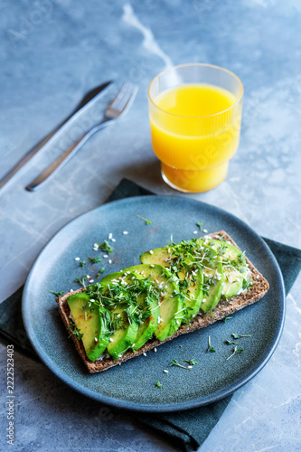 Nutritious morning breakfast with avocado rye sandwich and juice.
