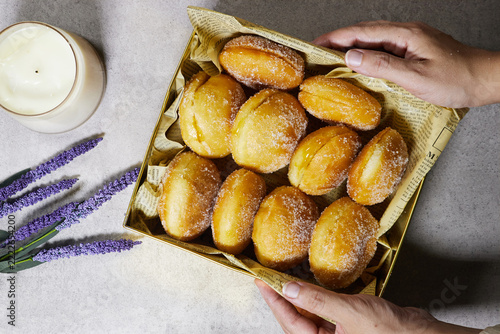 Hand Reaching for Sugar-Coated Donuts in Decorative Box With Candle and Lavender