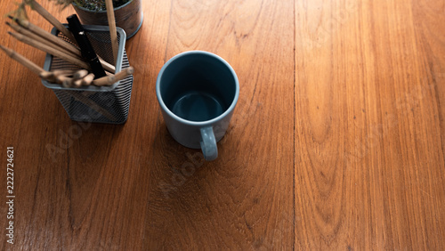 top view of a coffee mug with wooden pencils and pens on a wood grain desk.