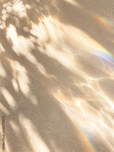 Warm beige paper texture with natural leaf shadows and rainbow sunlight
