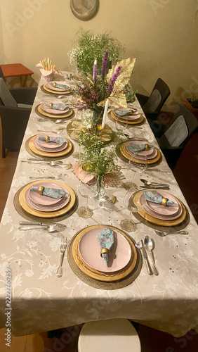 A bird's-eye view of an elegant holiday table set with pink tableware and gold accents for Christmas