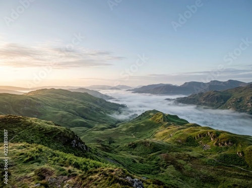 Green mountain valley landscape with morning mist and rolling hills