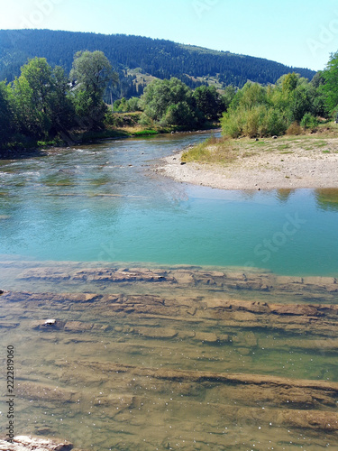 Clear mountain river with submerged layered rock formations in water