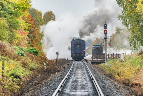 Retro steam train stands by the platform before departure.
