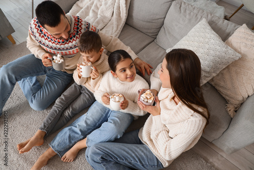 Happy parents with their little children drinking cocoa at home on winter day...