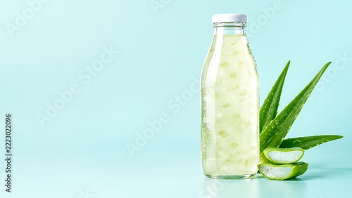 Aloe vera beverage bottle with fresh aloe leaves and natural plant ingredients on clean aqua background for refreshing wellness drink branding, packaging design, and FMCG marketing campaigns
