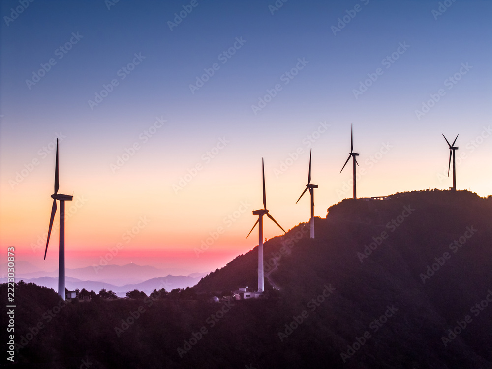 Obraz premium Wind turbines standing on mountain ridge at sunset