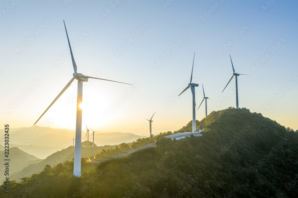 Fototapeta premium Wind turbines on mountain ridge at sunrise