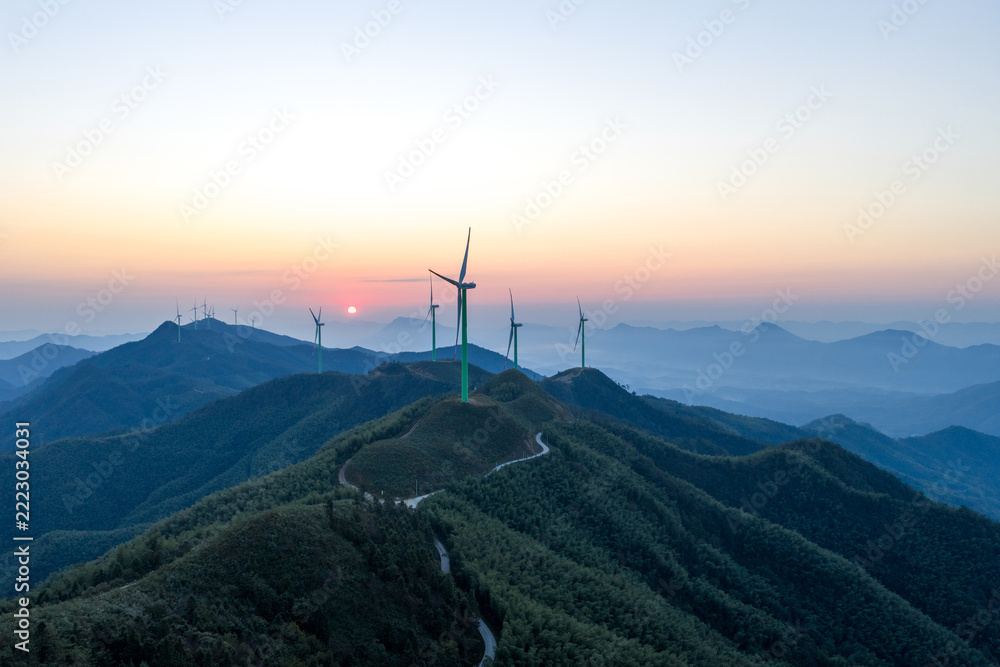 Obraz premium Wind turbines on green mountain peaks at sunset