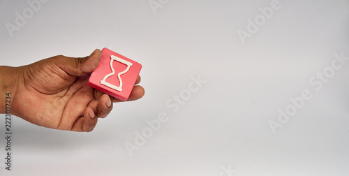 Obraz na plátně Hand holding pink block with white hourglass icon