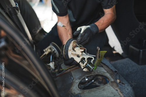 Auto mechanic removing an in-tank electric fuel pump module.