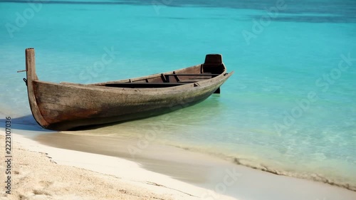 Static shot of wooden boat gently rocking on turquoise shallow beach water