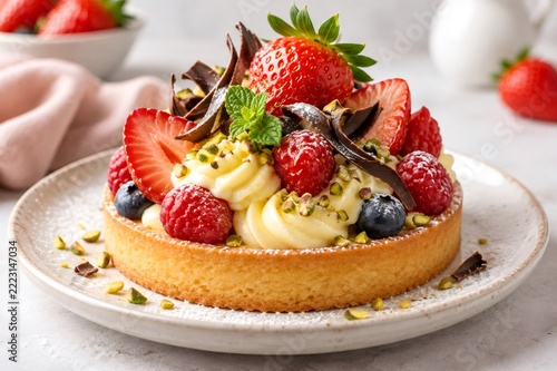Fruit tart with berries, cream, chocolate, and pistachios