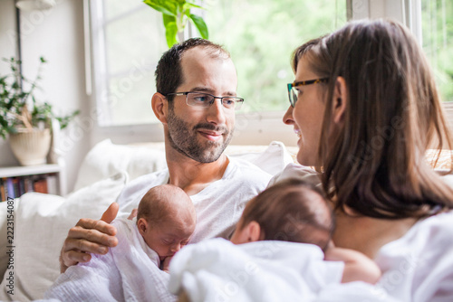 Happy couple holding their newborn twin babies at home