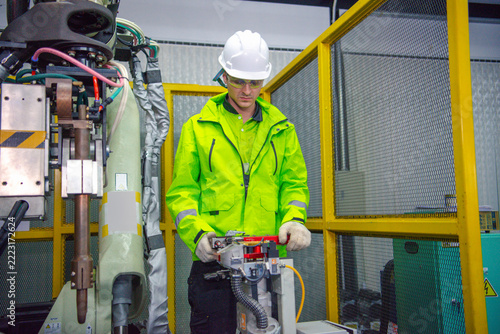 Robotic machine engineer checking the operation of a robot arm manufacturing machine