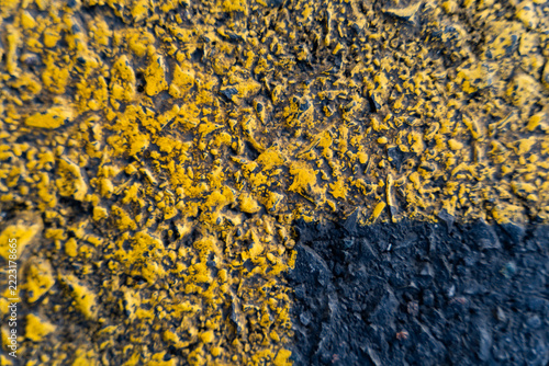 Close-up of rough textured yellow and black asphalt road markings