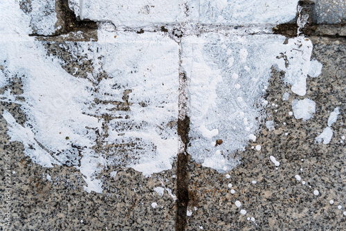 White paint splatter and footprint on cracked concrete sidewalk