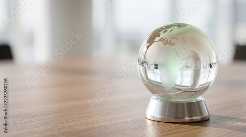 Glass globe with continents visible on a wooden table soft focus background