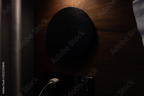 Contemporary hotel room interior featuring a dark wood panel with embedded charger and light controls