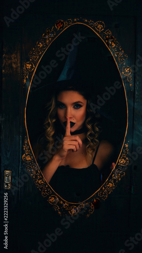 Obraz na plátně Young woman dressed as a halloween witch with dark makeup and a pointed hat, hol