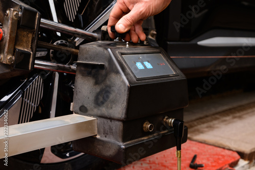 Mechanic uses equipment to check tire pressure at auto repair shop during daylight hours. Wheel alignment and alignment on the car service platform.