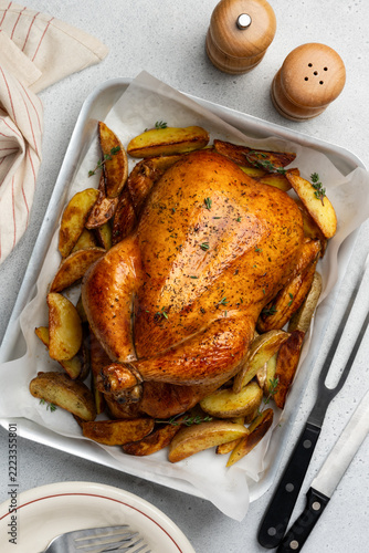Baked chicken with potatoes and herbs on a baking sheet. A delicious home-cooked dinner. Top view