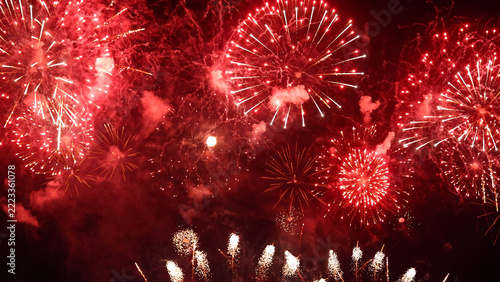 Vibrant red fireworks explode across the dark night sky with smoky textures, creating a festive background for Chinese New Year celebrations, Christmas, holiday events, and grand festivals