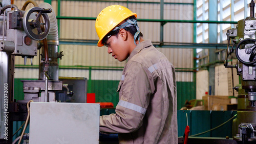 Industrial worker inspecting and handling parts on storage shelves in a manufacturing factory.