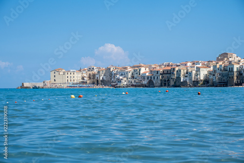 Famous beach of Cefalu, located on the northern coast of Sicily, Italy, with the historic village and its seafront buildings in the background