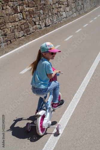 Child learning to ride bike with training wheels