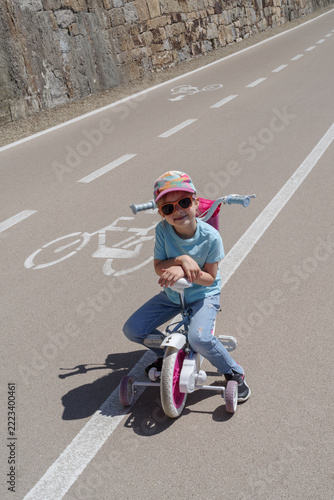 Child learning to ride bike with training wheels