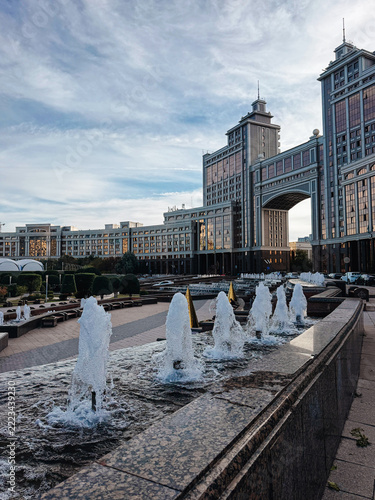 Flowing through fountain basin near KazMunayGas headquarters in Astana, with monumental arch, symmetrical towers 